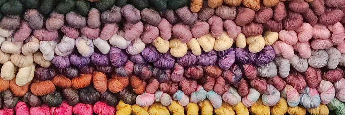 a photo composed of many skeins of colourful yarn, stacked on top of one another horizontally.